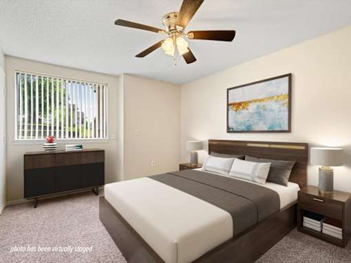 A bedroom with a bed, nightstand, and a painting on the wall.