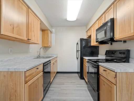 A kitchen with black appliances and wooden cabinets.