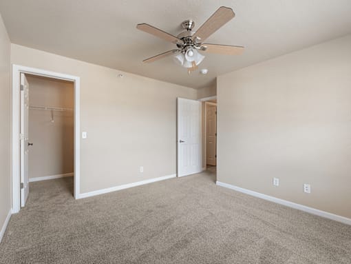 A room with a ceiling fan and carpeted floor.