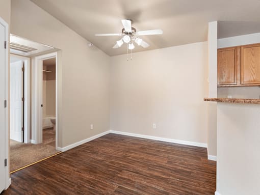 A room with a ceiling fan and wooden flooring.