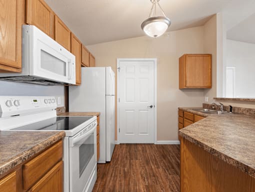 A kitchen with white appliances and wooden cabinets.