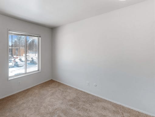 a bedroom with a large window and beige carpet