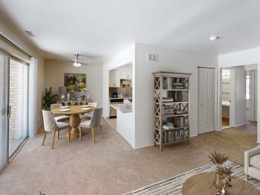 a living and dining room area with a table and chairs and a kitchen in the background