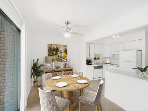 a dining area with a table and chairs and a kitchen in the background