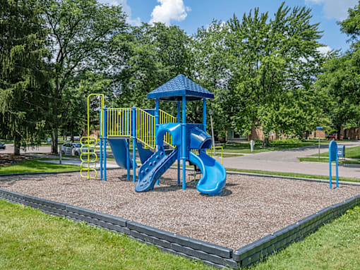 A playground with a blue slide and yellow safety barriers.