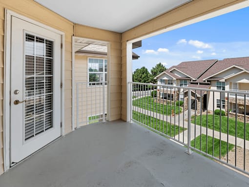 A view from the balcony of a house with a white door and a white fence.