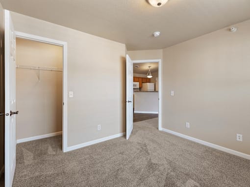 A room with a carpeted floor and a doorway leading to another room.