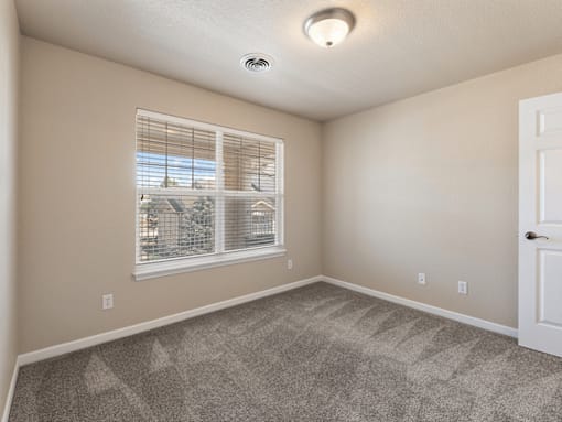 A room with a window and a carpeted floor.