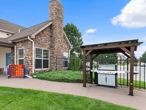 A brick house with a grill and a play structure outside.