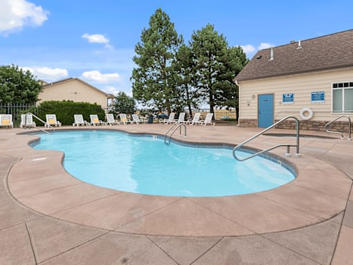 A small pool with a ladder and a building in the background.