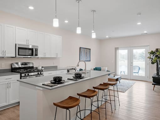 A kitchen with white cabinets and a bar area with stools.