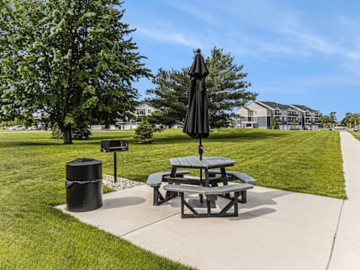 A black umbrella stands over a picnic table in a park.