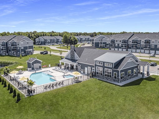 A large house with a pool in the foreground and several other houses in the background.
