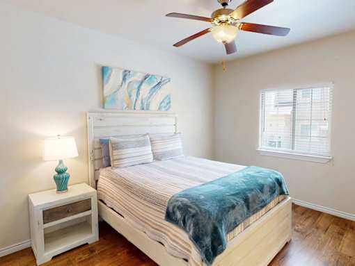 A bedroom with a bed, a nightstand, and a ceiling fan.
