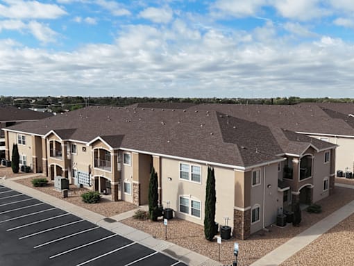 Apartment complex with a parking lot in front.