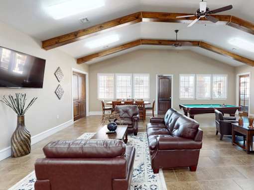 A living room with a pool table and leather furniture.