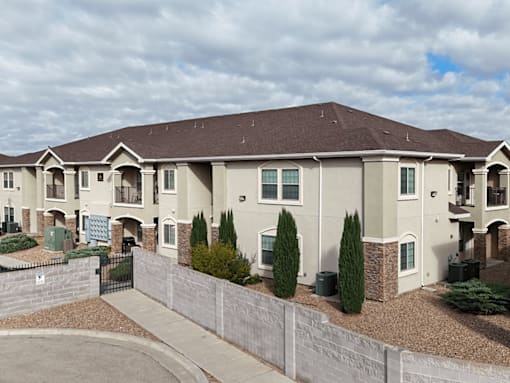 A large, two-story residential building with a brown roof and a grey exterior.