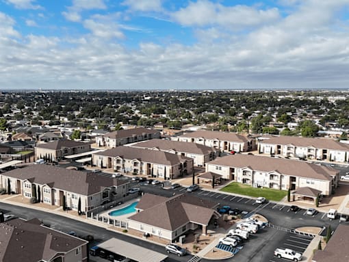 A large apartment complex with a swimming pool and a parking lot.