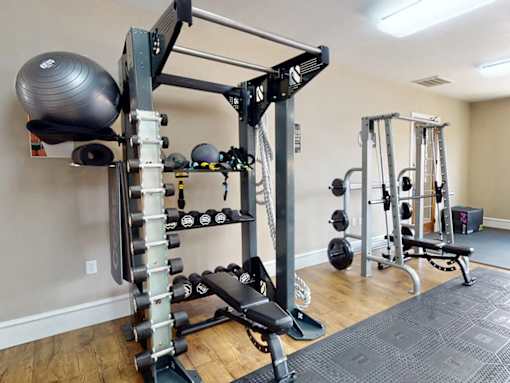 A home gym with a squat rack, dumbbells, and a bench.