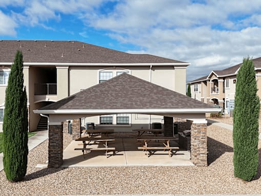 A covered patio area with a table and chairs is in front of a house.