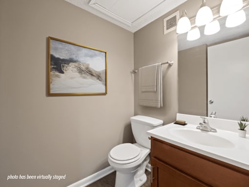 A bathroom with a white toilet, a white sink, and a painting on the wall.