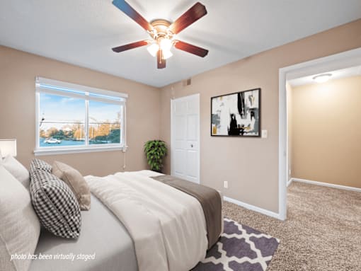 A bedroom with a bed, a ceiling fan, and a window overlooking a pool.