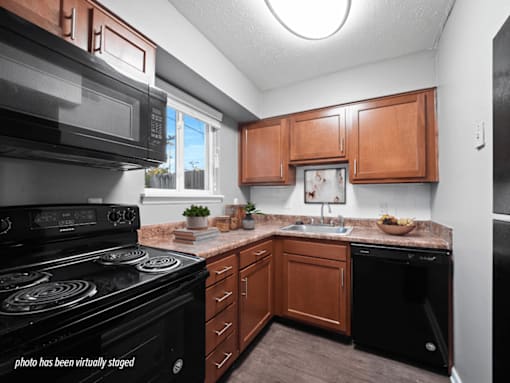 A kitchen with black appliances and wooden cabinets.