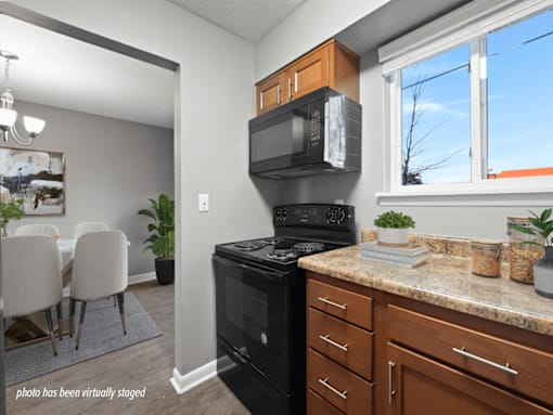 A kitchen with a black stove and wooden cabinets.