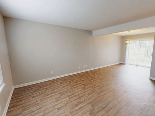 A room with wooden flooring and a window with blinds.