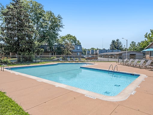 A large outdoor swimming pool surrounded by trees and lounge chairs.