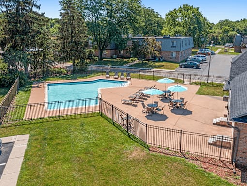 A pool surrounded by a fence and chairs.