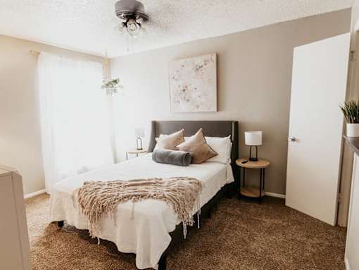 A bedroom with a bed, nightstands, and a painting on the wall.