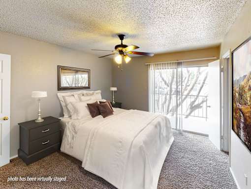 A bedroom with a bed, nightstand, and a ceiling fan.