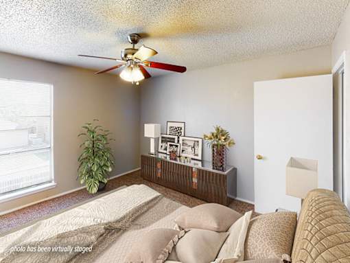 A living room with a couch, a ceiling fan, and a window.