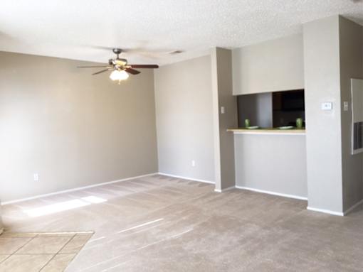 A room with a ceiling fan and a kitchenette.
