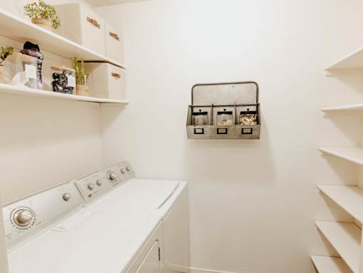 A white washing machine in a laundry room with shelves and storage.