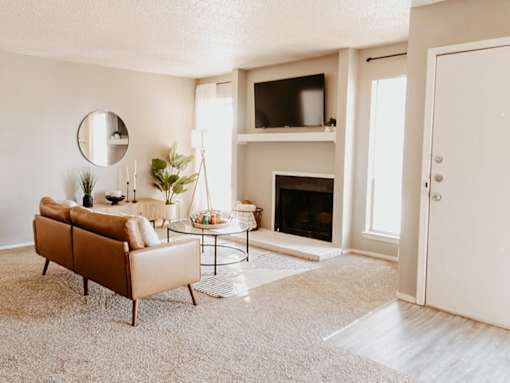 A living room with a brown sofa, a fireplace, and a mirror on the wall.