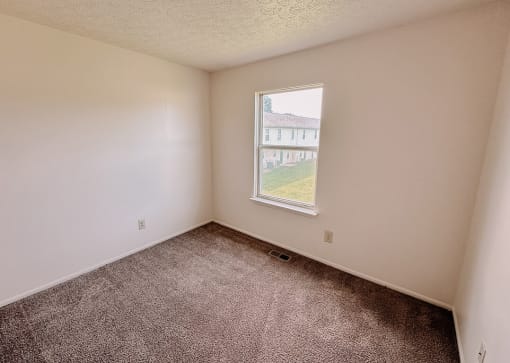 an empty room with a window and carpet