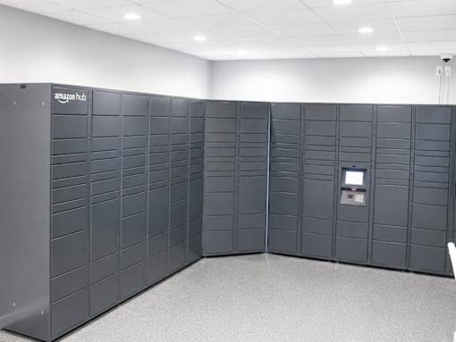 A row of Amazon locker units are lined up in a room.