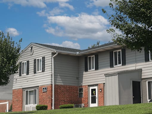 A grey house with a red brick base and a black door.