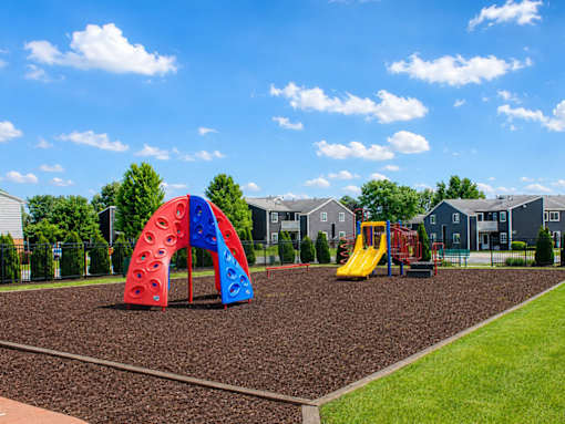 A playground with a red and blue arch and a yellow slide.