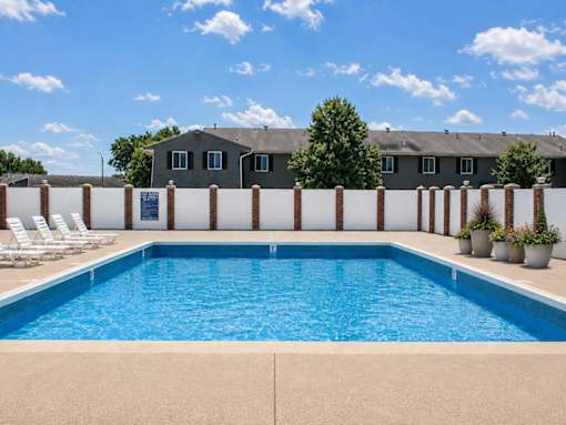 A swimming pool surrounded by a white fence and chairs.