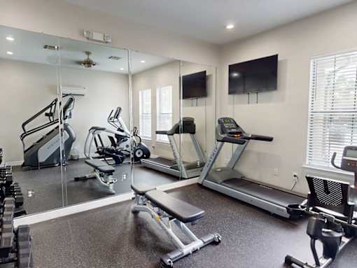 A spacious gym with treadmills, elliptical machines, and a television.