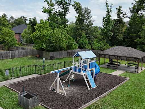 A playground with a blue slide and a brown sandbox.