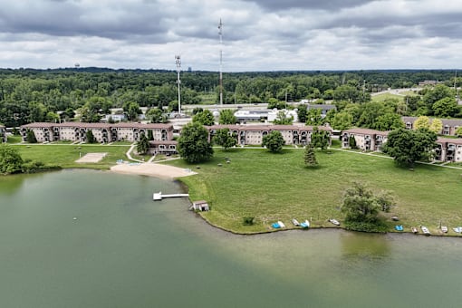 A large building complex sits on a grassy area next to a body of water.