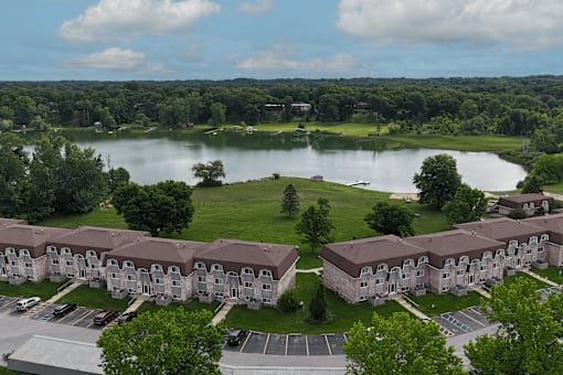 A large building complex is situated in front of a lake.