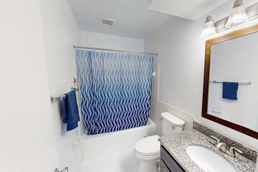 A bathroom with a white toilet, sink, and a blue shower curtain.