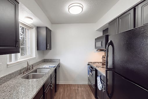 A kitchen with black cabinets and a granite countertop.