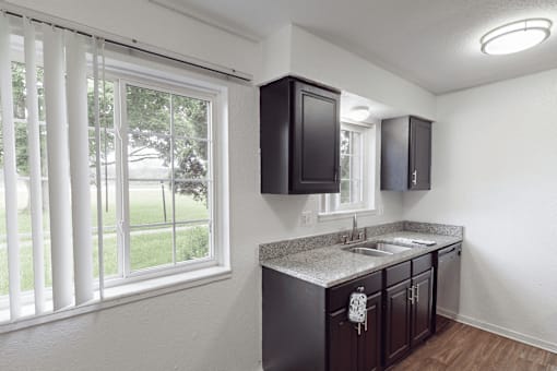 A kitchen with dark brown cabinets and a granite countertop.