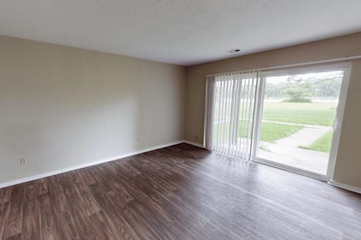 A room with wooden flooring and sliding glass doors.
